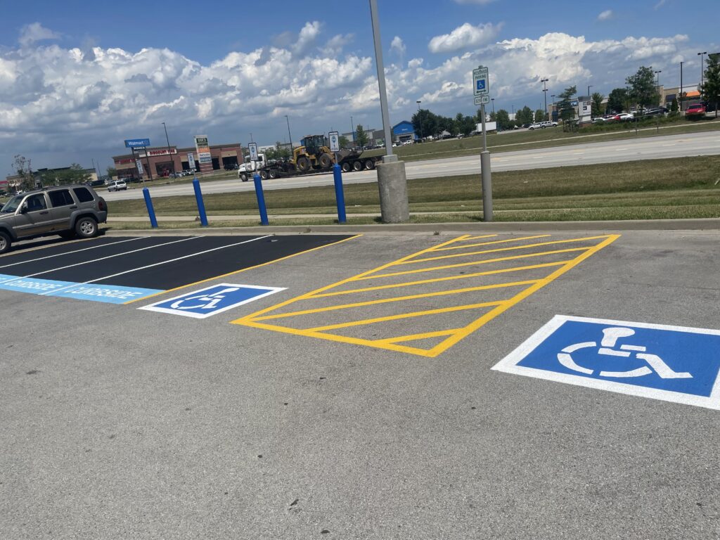 Two ADA parking stalls with ADA symbols with white boarder, a blue background, and a white ADA symbol. Between the two the ADA parking stalls is a hatched area.
