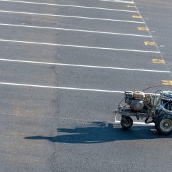 line-painting being done in parking lot using a line-striping machine